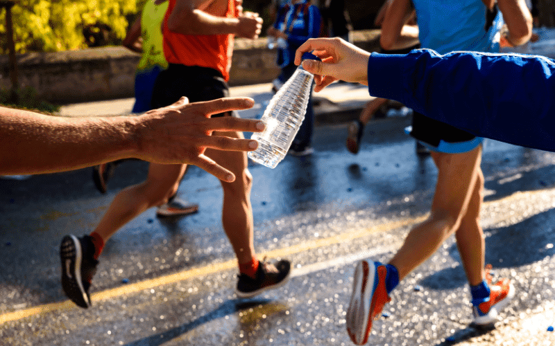 A runner on a track, alternating between sprints and slow jogs, with a stopwatch and water bottle nearby. The sun is setting in the background